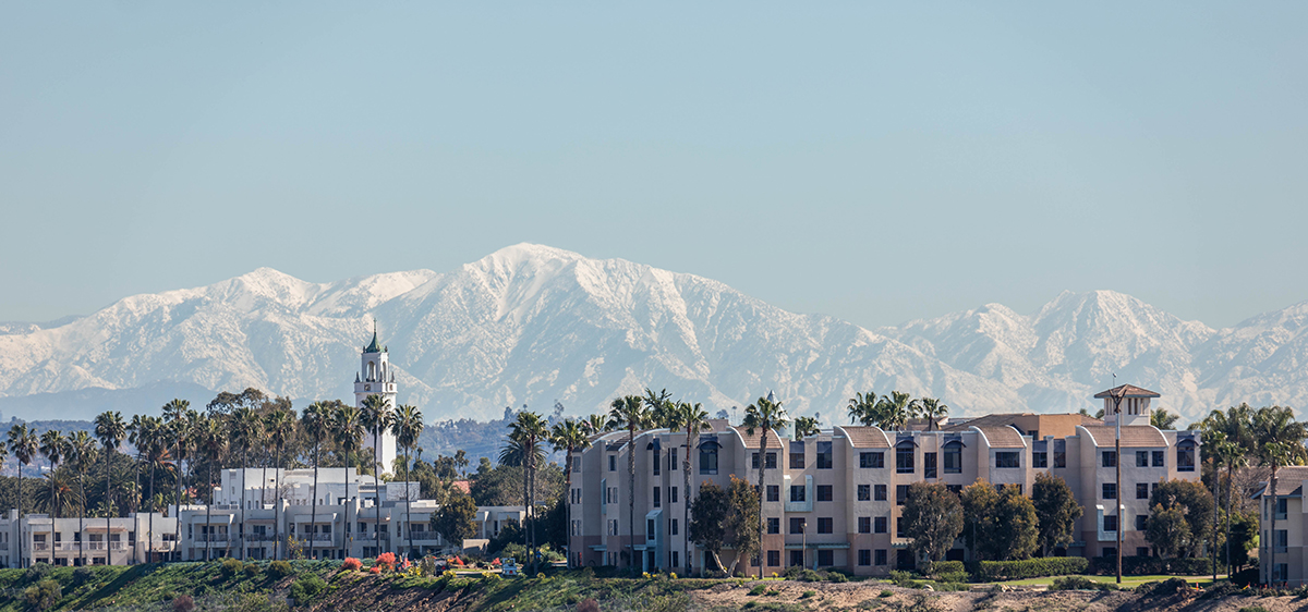 A view of the LMU Bluff with snow-capped mountains in the far background and a blue sky.